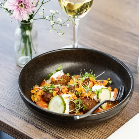 Elegant hotel dining with gourmet dish, delicate flowers, and glass of wine, highlighting refined guest experience.