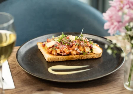 Savour gourmet bruschetta with wine, fresh flowers in an elegant hotel dining setting. Delightful culinary experience.