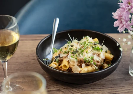 Elegant dining with delicious pasta and wine in a cosy hotel restaurant setting, perfect for a relaxing culinary experience.