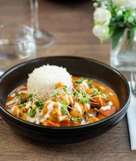 Delicious curry with rice served in elegant dining setting, featuring fresh microgreens in a luxurious hotel restaurant.