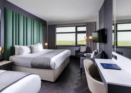 Stylish hotel room with king-size bed, scenic window view, modern decor, desk, seating area, and flat-screen TV.