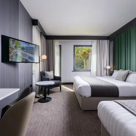 Elegant hotel room with large bed, flat-screen TV, and garden view, perfect for a relaxing stay.