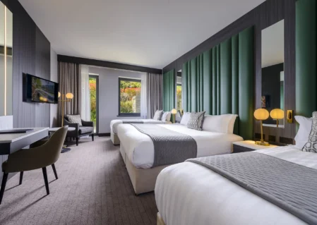 Spacious modern hotel room with twin beds, elegant decor, and scenic window view, ideal for relaxation.