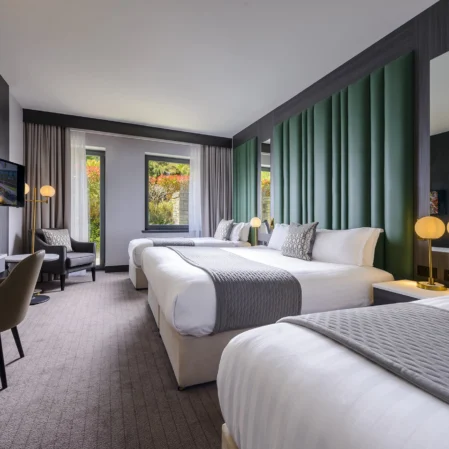 Spacious modern hotel room with twin beds, elegant decor, and scenic window view, ideal for relaxation.