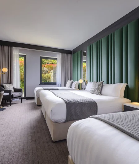Spacious modern hotel room with twin beds, elegant decor, and scenic window view, ideal for relaxation.