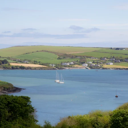 Stunning sea view with sailboats and lush green hills from hotel room, ideal for a coastal retreat.