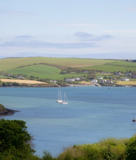 Stunning sea view with sailboats and lush green hills from hotel room, ideal for a coastal retreat.