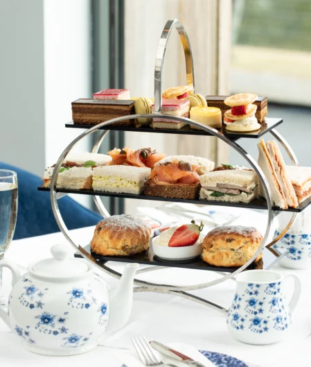 Enjoy exquisite afternoon tea with sandwiches and pastries in a stylish hotel dining room with charming decor.