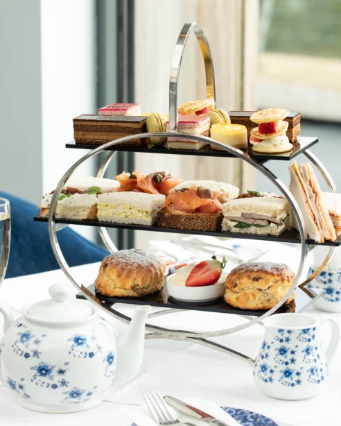 Enjoy exquisite afternoon tea with sandwiches and pastries in a stylish hotel dining room with charming decor.