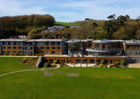 Modern hotel with lush gardens, terrace seating, and forest backdrop, ideal for relaxing stays and scenic views.