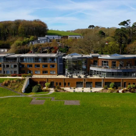 Modern hotel with lush gardens, terrace seating, and forest backdrop, ideal for relaxing stays and scenic views.
