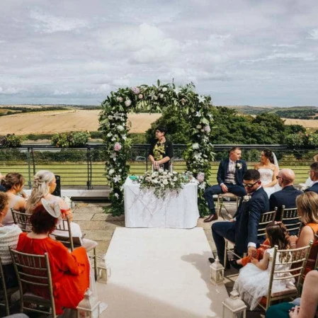 Beautiful hotel terrace with stunning countryside views, elegant wedding setup, and lush greenery under a clear blue sky.