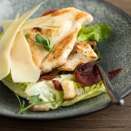 Elegantly plated Caesar salad with grilled chicken, fresh lettuce, and parmesan shavings at hotel dining.