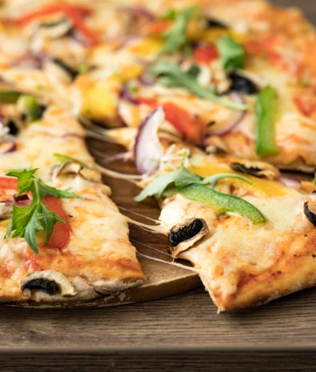 Freshly baked vegetarian pizza with colourful toppings including peppers and mushrooms at hotel restaurant.