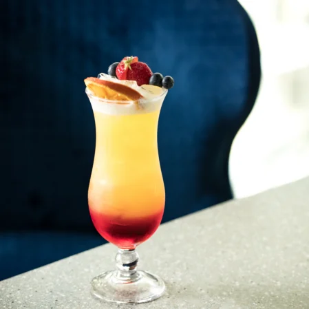 Refreshing tropical cocktail with berries garnishing, on elegant marble table, cosy relaxed atmosphere, luxury hotel bar.