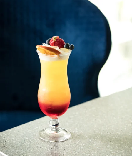 Refreshing tropical cocktail with berries garnishing, on elegant marble table, cosy relaxed atmosphere, luxury hotel bar.