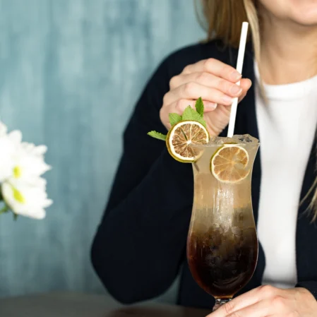 Guest enjoying a refreshing cocktail with lemon slices at the hotel bar, featuring elegant decor and a welcoming atmosphere.