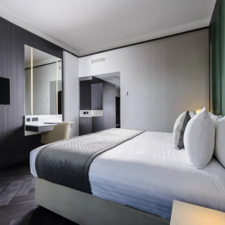 Elegant hotel room with plush king bed, modern décor, wall-mounted TV, and ambient lighting for a relaxing stay.