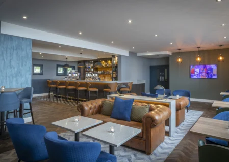 Cosy hotel lounge with plush seating, stylish bar, ambient lighting, welcoming atmosphere, perfect for relaxation.