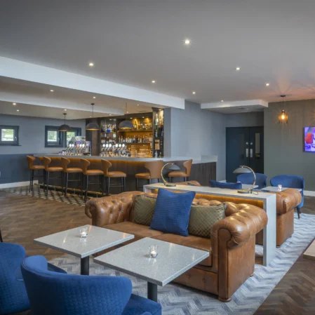 Cosy hotel lounge with plush seating, stylish bar, ambient lighting, welcoming atmosphere, perfect for relaxation.