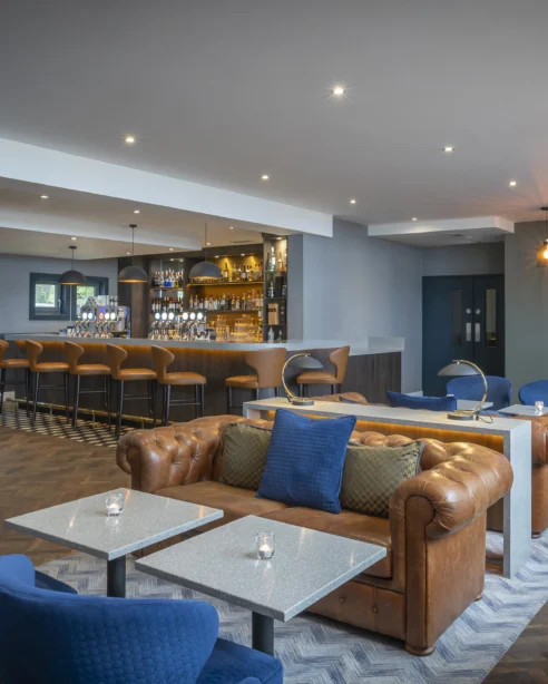 Cosy hotel lounge with plush seating, stylish bar, ambient lighting, welcoming atmosphere, perfect for relaxation.