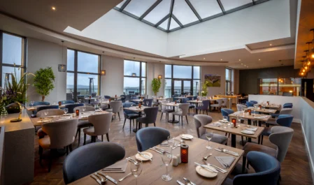 Elegant hotel dining area with sea views, skylight, cosy seating, and modern décor perfect for a relaxing meal.