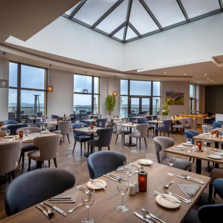 Elegant hotel dining area with sea views, skylight, cosy seating, and modern décor perfect for a relaxing meal.