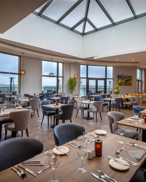 Elegant hotel dining area with sea views, skylight, cosy seating, and modern décor perfect for a relaxing meal.