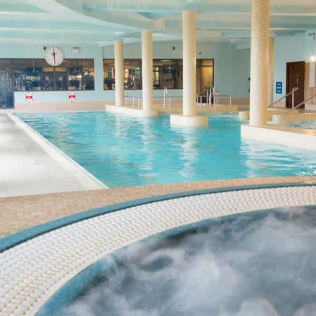 Inviting indoor swimming pool with jacuzzi, loungers, and modern decor at luxury hotel for a relaxing stay.