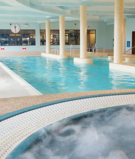 Inviting indoor swimming pool with jacuzzi, loungers, and modern decor at luxury hotel for a relaxing stay.