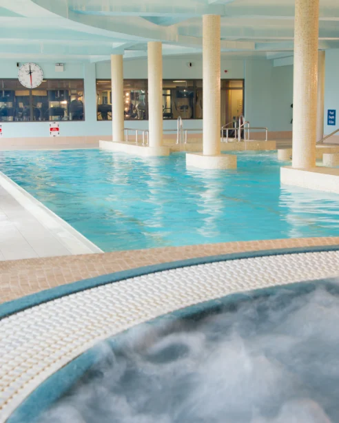 Inviting indoor swimming pool with jacuzzi, loungers, and modern decor at luxury hotel for a relaxing stay.