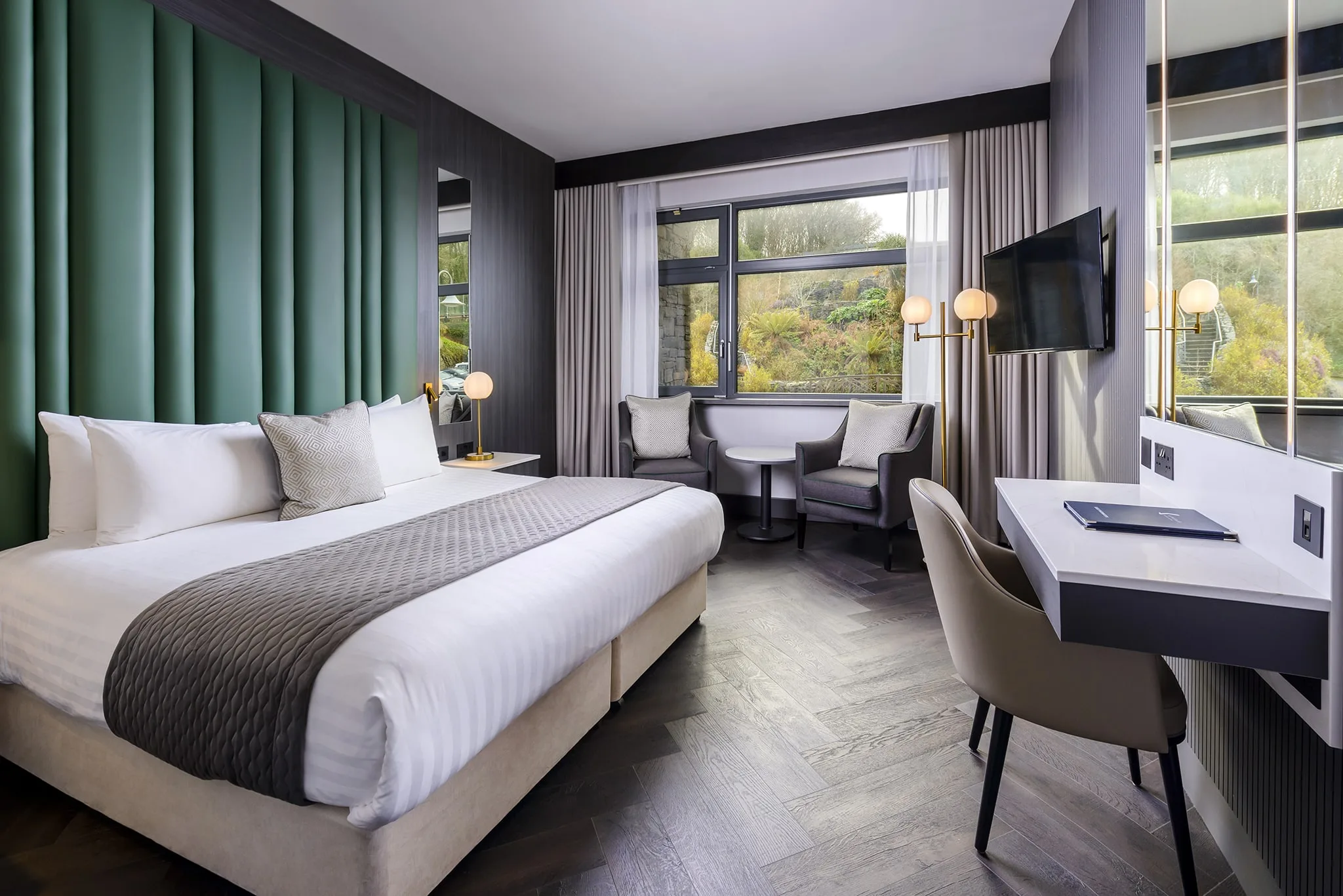 Modern hotel room with king-size bed, stylish decor, large window view, comfy seating, and workspace. Ideal for relaxation.