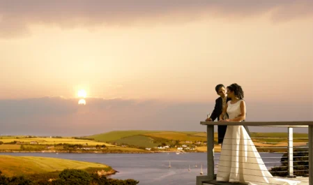 Couple enjoys a romantic sunset over serene coastal views from hotel balcony, perfect for a relaxing and memorable getaway.