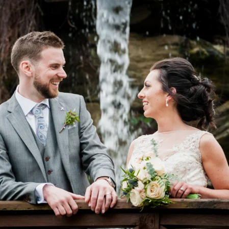 Happy couple enjoying serene waterfall view at beautiful hotel garden with lush greenery.