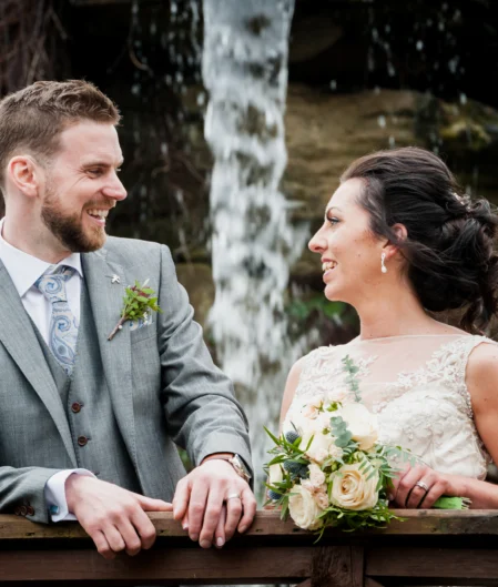 Happy couple enjoying serene waterfall view at beautiful hotel garden with lush greenery.