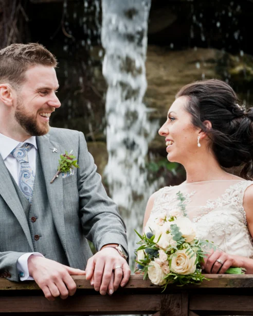 Happy couple enjoying serene waterfall view at beautiful hotel garden with lush greenery.