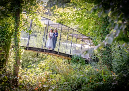 Lush garden view with a romantic couple on an arched bridge at a serene hotel retreat.