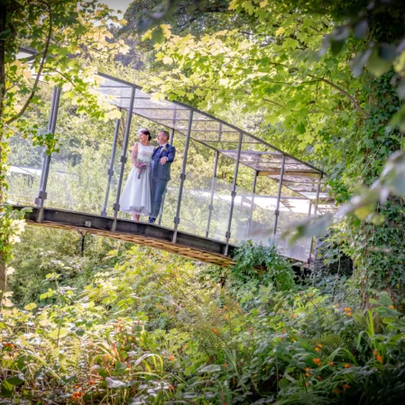 Lush garden view with a romantic couple on an arched bridge at a serene hotel retreat.