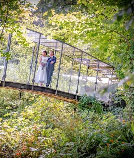 Lush garden view with a romantic couple on an arched bridge at a serene hotel retreat.