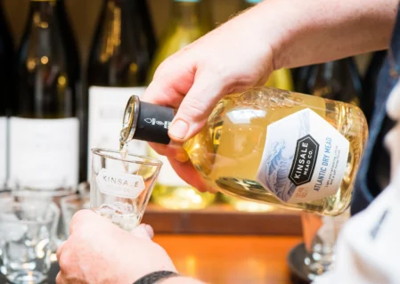 Guest enjoying a fine mead tasting experience at the hotel's elegant bar with premium bottle selection in background.