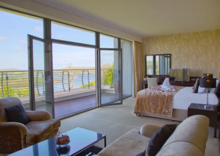 Spacious hotel suite with balcony, sea view, plush seating, and modern amenities for a relaxing stay.