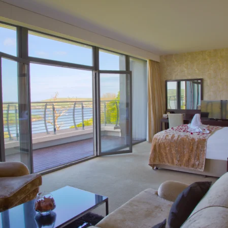 Spacious hotel suite with balcony, sea view, plush seating, and modern amenities for a relaxing stay.