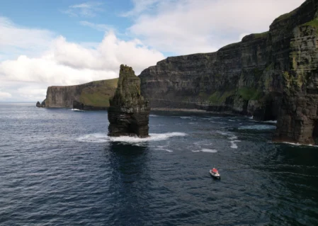 Spectacular sea cliffs with a lone boat, offering stunning coastal views and serene exploration opportunities for hotel guests.