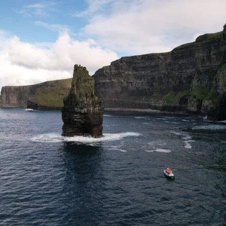 Spectacular sea cliffs with a lone boat, offering stunning coastal views and serene exploration opportunities for hotel guests.