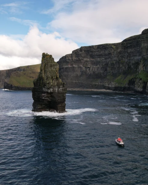 Spectacular sea cliffs with a lone boat, offering stunning coastal views and serene exploration opportunities for hotel guests.