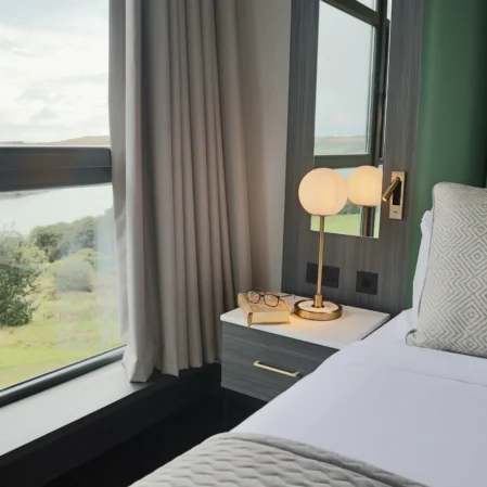 Luxurious hotel room with scenic lake view, cosy bed, bedside lamp, and modern decor for a relaxing stay.