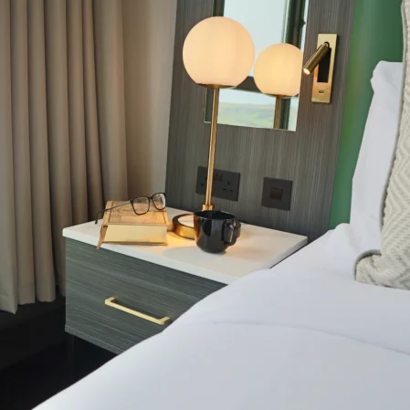 Cosy hotel room with comfortable bed, bedside table, lamp, scenic window view, perfect for a relaxing stay.