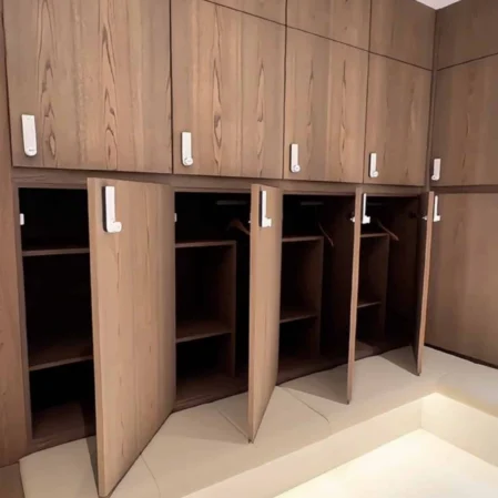 Spacious wooden wardrobes with open doors in modern hotel room, featuring elegant design and ample storage for guests.