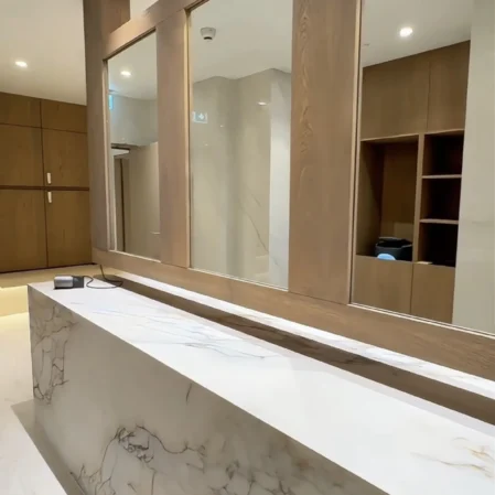 Elegant hotel reception with marble desk, warm lighting, and wooden accents, offering a welcoming first impression.