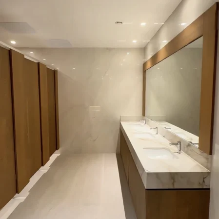 Luxurious hotel bathroom with dual sinks, large mirror, elegant lighting, and marble finishes for a premium experience.